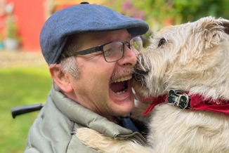 Borger i kørestol med en hund på skødet.